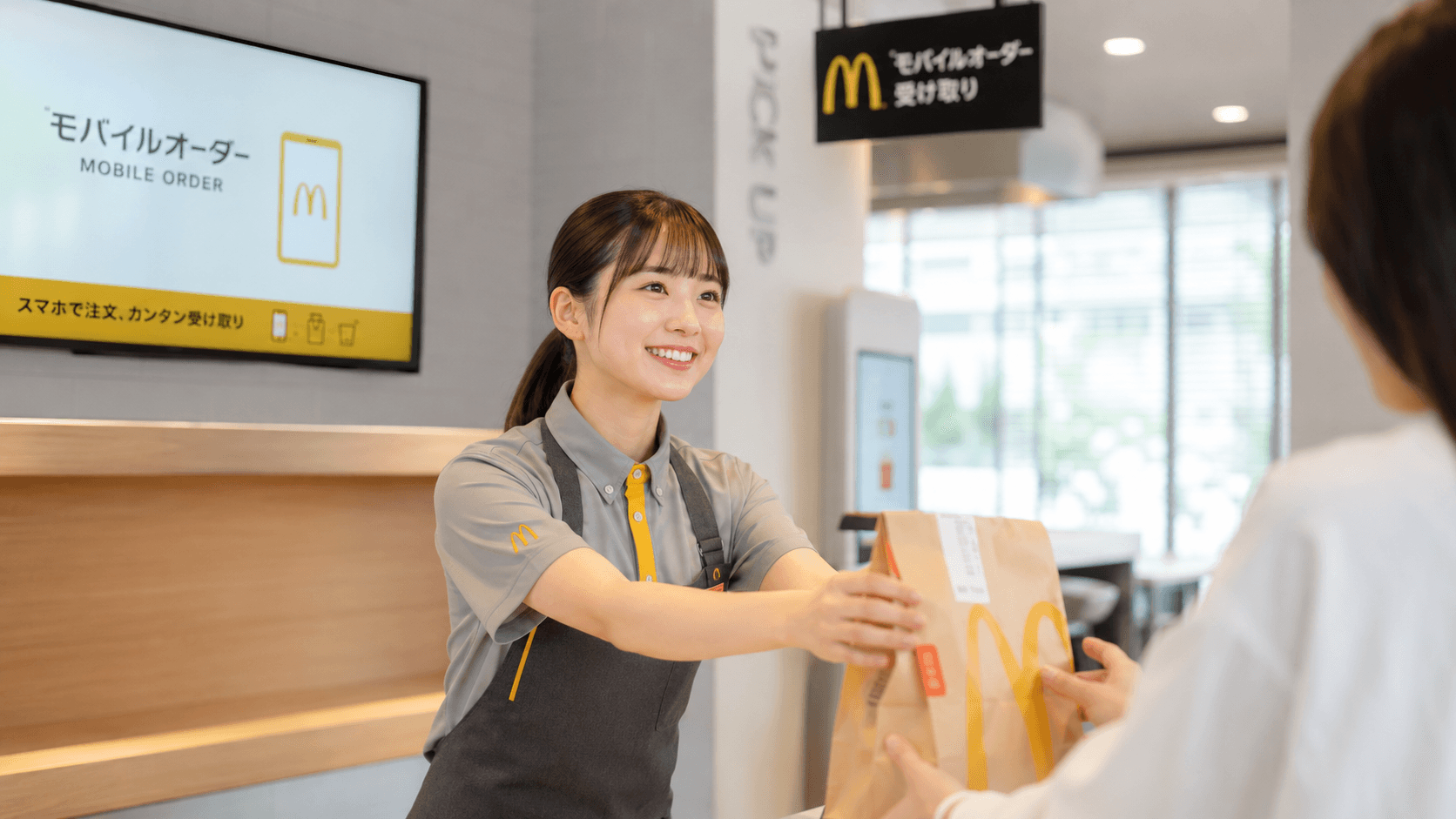 モバイルオーダーの商品を笑顔で受け渡すスタッフ